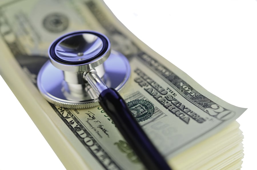 Stethoscope on pile of U.S. twenty-dollar bills isolated on white background