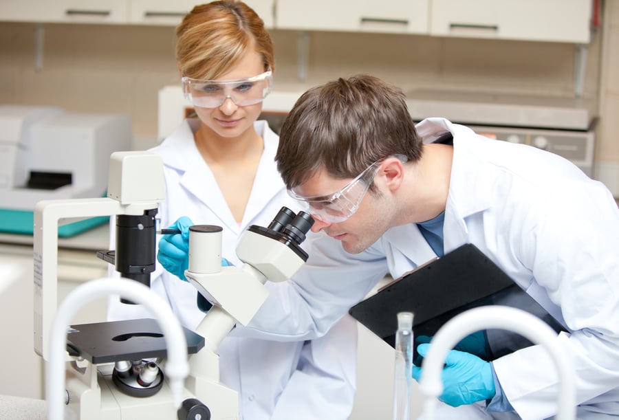 Two scientists observing something with a microscope in their laboratory